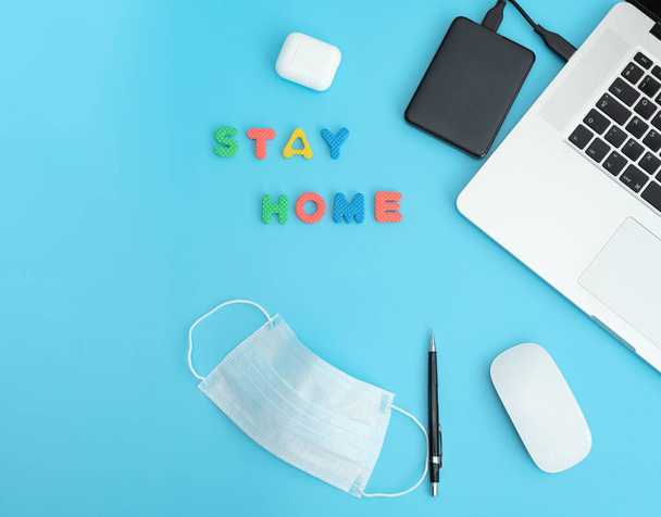 Work at home concept. Mockup, top view of workplace with laptop, earphones, mouse, pencil, letters and protective medical face mask. Remote work and education during coronavirus pandemic in the world. - Fotó, kép