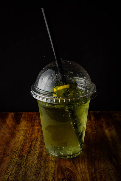 Холодный освежающий напиток в стакане с ломтиками лайма, мятой и кубиками льда. Летний лимонад с цитрусовым крупным планом
 - Фото, изображение