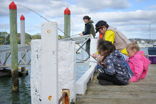 Nueva Zelanda pesca familiar juntos desde un embarcadero en Taipa Bay-Mangonui en Northland Isla Norte de Nueva Zelanda. Gente real. Copiar espacio
. - Foto, Imagen