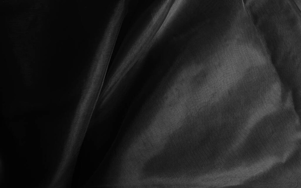 Crumpled charmeuse cloth in monochrome, black background with light and shadow  - Photo, Image