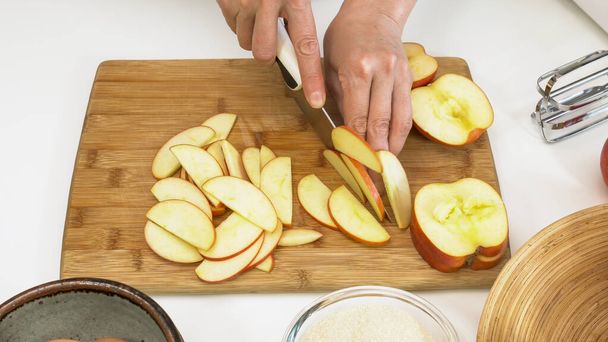 Woman slicing apples. Close up on a wooden cutting board on white background - 写真・画像