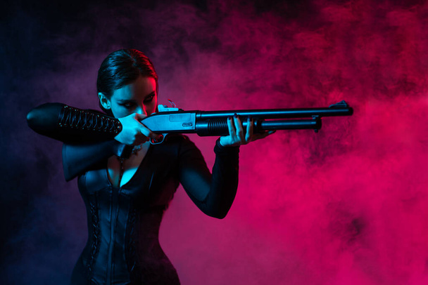Young woman with a gun posing in studio - Foto, imagen