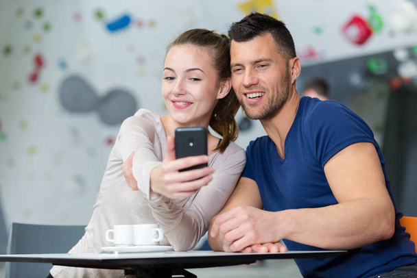 beautiful happy couple in sportswear doing selfie using smartphone - Photo, Image