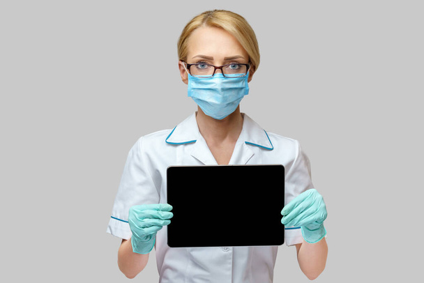 medical doctor nurse woman wearing protective mask and gloves - holding tablet pc - Fotoğraf, Görsel