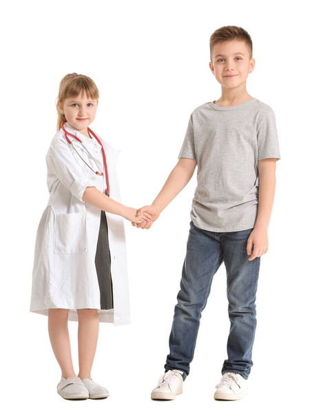 Cute little doctor with patient shaking hands on white background - Fotó, kép