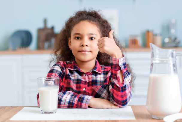 Маленька афро-американська дівчина з молоком на кухні. - Фото, зображення