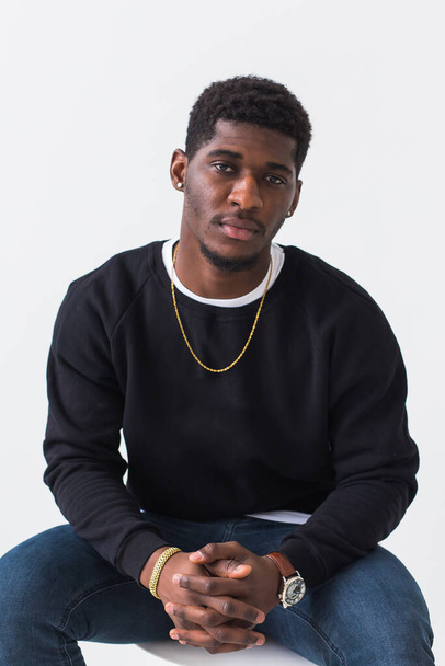 Handsome African American man posing in black sweatshirt on a white background. Youth street fashion photo with afro hairstyle. - Foto, afbeelding
