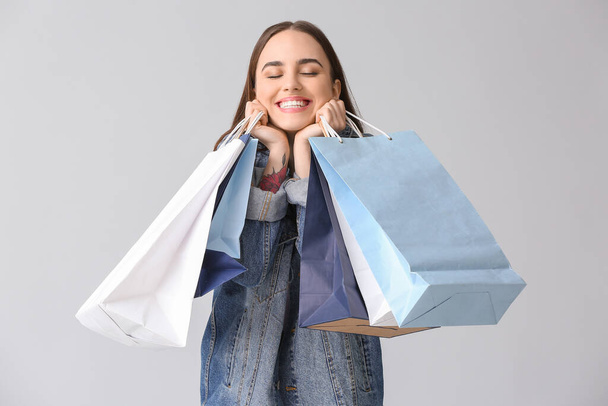 Mujer joven con bolsas de compras sobre fondo gris
 - Foto, imagen