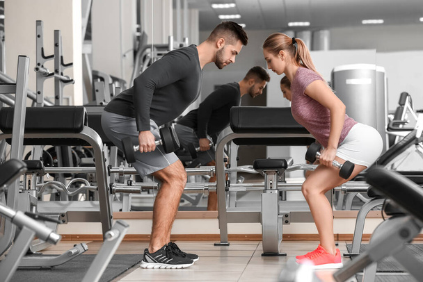 sportif jeune couple entraînement avec haltères dans la salle de gym
 - Photo, image