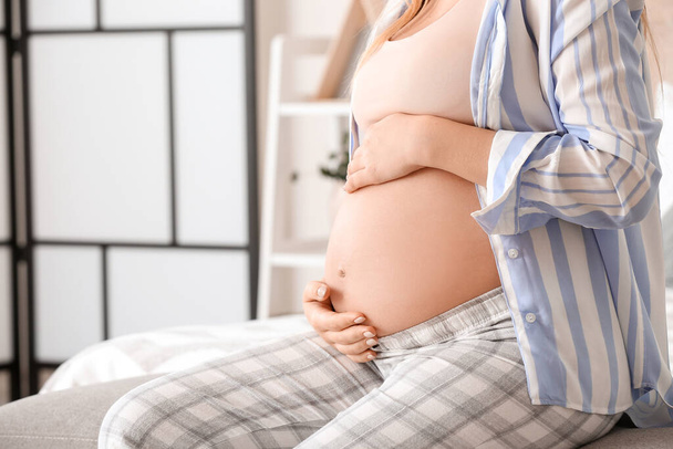 Mooie jonge zwangere vrouw in slaapkamer - Foto, afbeelding