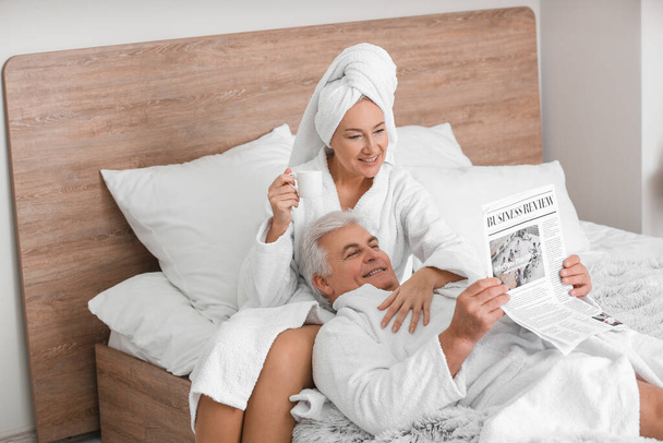 Kypsä pari käsittelyssä sanomalehti makuuhuoneessa
 - Valokuva, kuva
