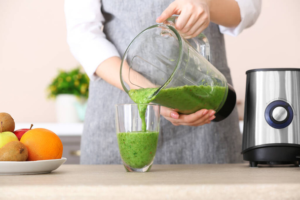 Woman pouring healthy smoothie into glass in kitchen - Photo, Image