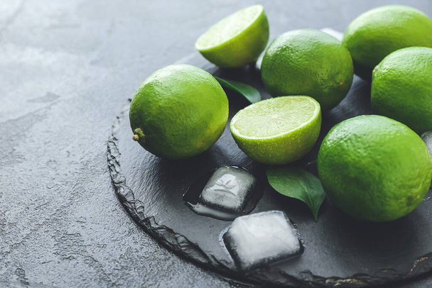 Fresh limes and ice cubes on dark background - Photo, Image