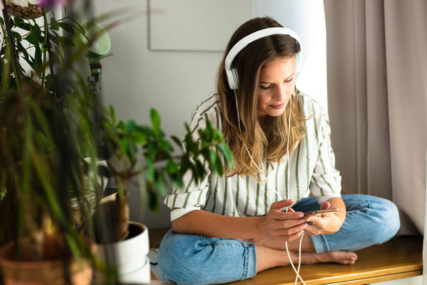happy single woman comunicating and listening music on the desk next to the plants and bright window, work from home, stay at home. - Foto, Bild