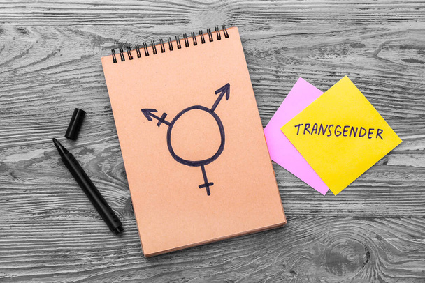 Notebook with drawn symbol of transgender on wooden background - Photo, Image