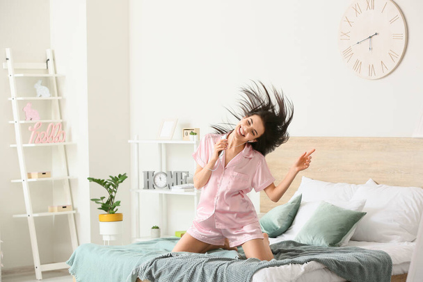 Όμορφη νεαρή γυναίκα που ακούει μουσική και χορεύει στην κρεβατοκάμαρα - Φωτογραφία, εικόνα