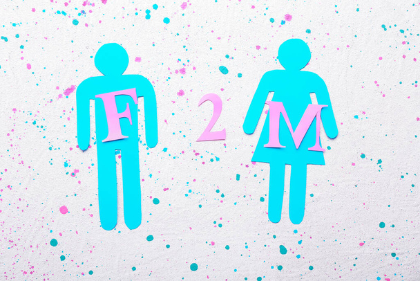 Mannelijke en vrouwelijke figuren en afkorting F2M op witte achtergrond. Begrip transgender - Foto, afbeelding