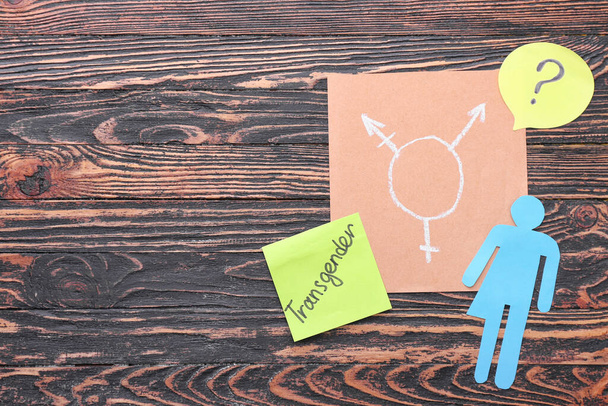 Трансгендерная фигура с символом и вопросительным знаком на деревянном фоне
 - Фото, изображение