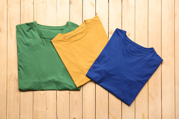 Different stylish t-shirts on wooden background - Фото, зображення