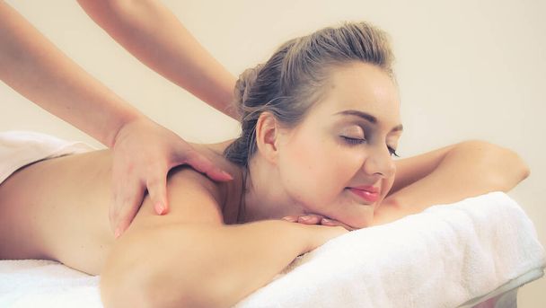 Relaxed woman getting back massage in luxury spa with professional massage therapist. Wellness, healing and relaxation concept. - Photo, image