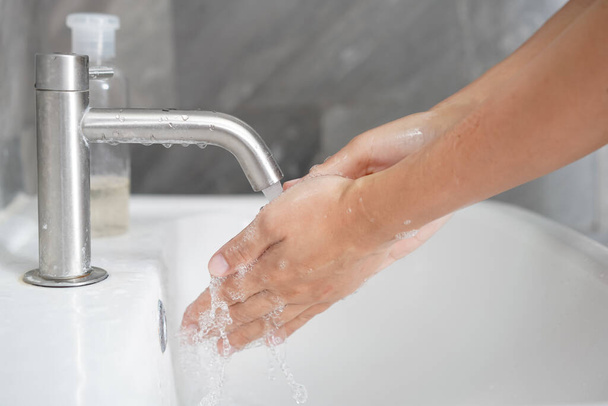 Hands washing for prevention of novel Coronavirus Disease 2019 or COVID-19 . People wash hands at bathroom sink to clean the virus infection. - Foto, immagini