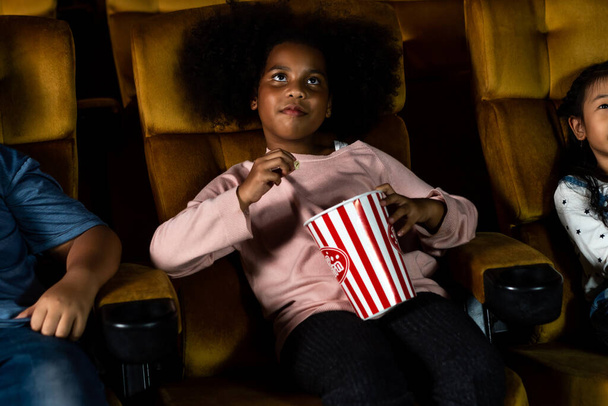 Three children having fun and enjoy watching movie in cinema - Valokuva, kuva