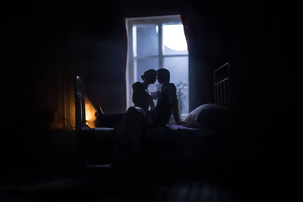 Una casa de muñecas realista dormitorio con muebles y ventana por la noche. Pareja romántica sentada en la ventana. Hombre y mujer haciendo el amor en el dormitorio. Decoración de mesa de arte. Enfoque selectivo. - Foto, imagen
