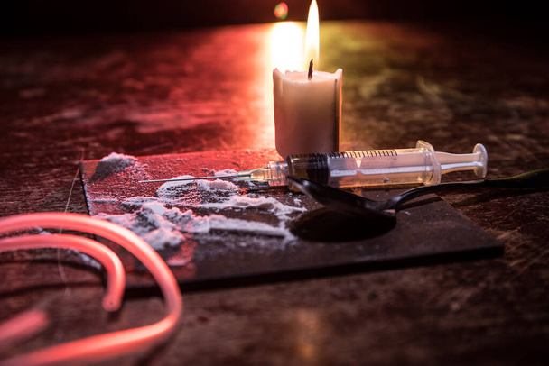 Narcotic drug problem concept. Drug syringe and narcotic attributes on wooden table. Purchase, possession and sale of drugs is punishable by law. Creative artwork decoration - Photo, Image