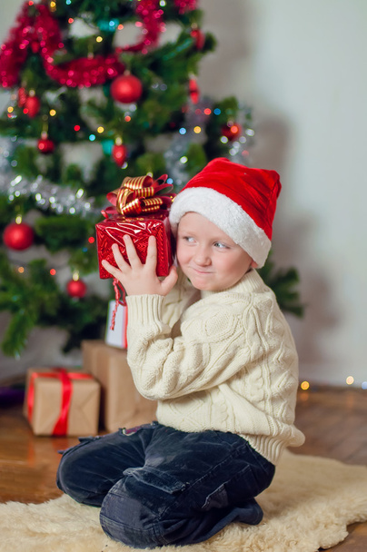 Little boy in santa hat near Christmas tree - Fotografie, Obrázek
