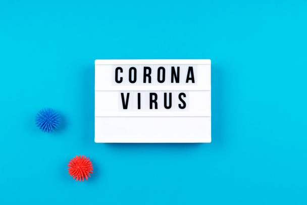 Lightbox with Coronavirus wording and plastic balls aka viruses on the blue background. Epidemic, social isolation, coronavirus COVID-19 concept - Zdjęcie, obraz