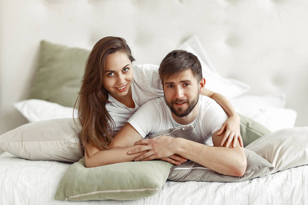 Couple sitting on a bed in a room - 写真・画像