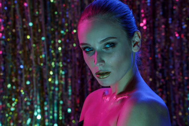 Beauty portrait of a High Fashion model woman in colorful bright neon lights posing in studio, night club On colourful vivid sequin background - Foto, immagini