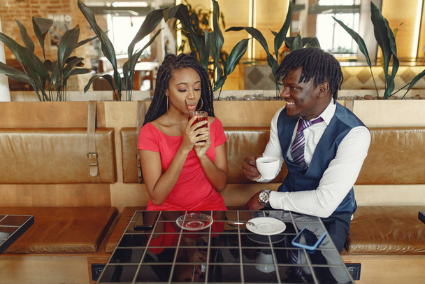 Stylish black couple sitting in a cafe and drinking a coffee - Foto, imagen