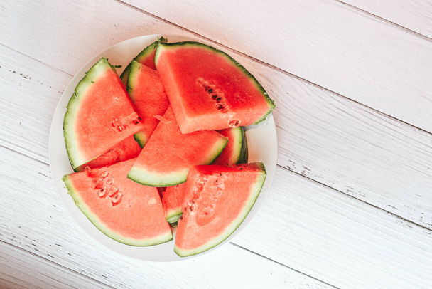 Pieces of fresh red watermelon on a clean white wooden table - Foto, afbeelding