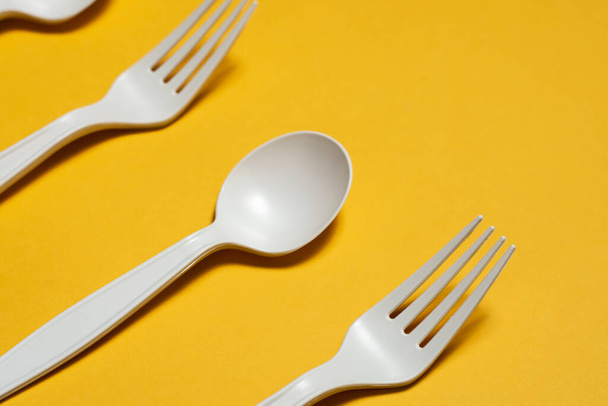 disposable spoons and forks of corn starch on a yellow background. biodegradable environmentally friendly disposable tableware. isolate. replacement of plastic with modern biomaterials. close-up - Photo, Image