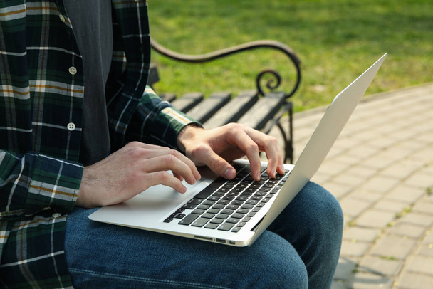 Man with laptop works in park. Outdoor work - Photo, image