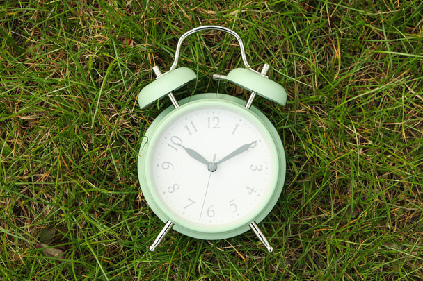 Reloj despertador sobre fondo de hierba verde. Primavera
 - Foto, Imagen