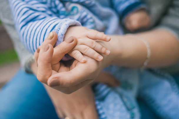 Moeder houdt zachtjes de hand van haar pasgeboren zoon vast - Foto, afbeelding