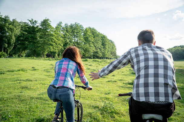 Un tipo con una chica montando bicicletas en un césped verde
 - Foto, imagen
