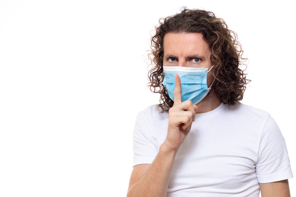 Людина в медичній масці дивиться в камеру. Чоловік стоїть в захисній медичній масці проти вірусів та інфекцій ізольованої студії. Пандемічна коронавірусна епідемія ковід-19
 - Фото, зображення