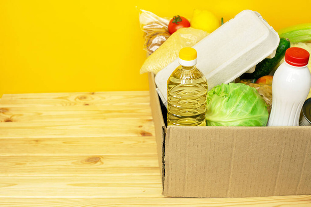 Varios alimentos enlatados, huevos y verduras en una caja de cartón
. - Foto, Imagen