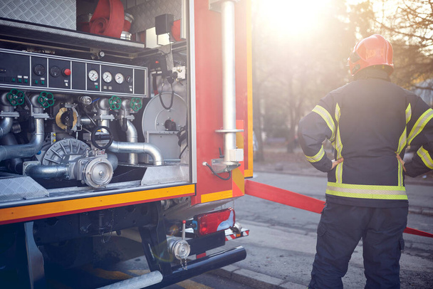 Fireman firefighter in action standing near a fire truck.  Attack, danger,fire. - Foto, afbeelding