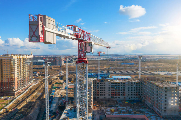 Stavební jeřáby postavily vícepodlažní budovu s byty na pozadí modré oblohy s mraky, letecký výhled - Fotografie, Obrázek