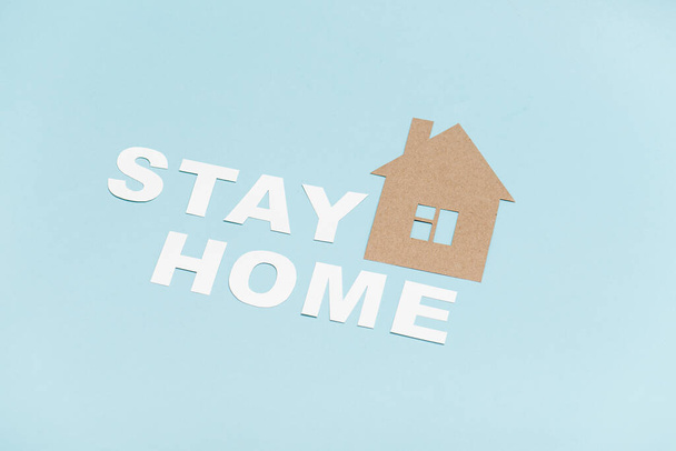 Cardboard stay home message laid on a blue surface along with house shape - Fotó, kép