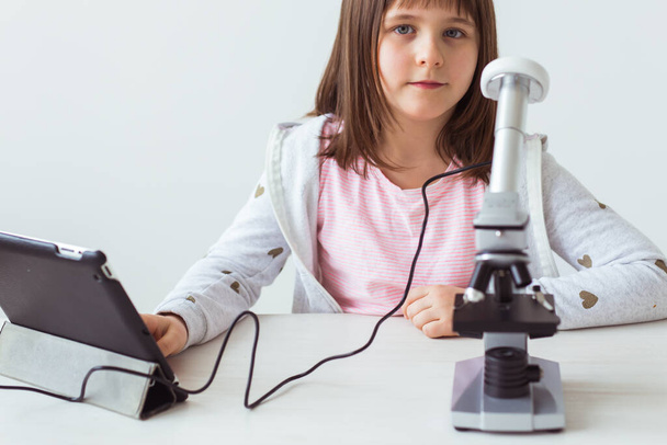 Fen sınıfındaki çocuk mikroskop kullanıyor. Teknolojiler, çocuklar ve öğrenme kavramı. - Fotoğraf, Görsel