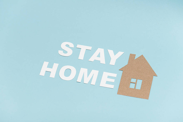Cartão ficar em casa mensagem colocada em uma superfície azul, juntamente com a forma da casa
 - Foto, Imagem