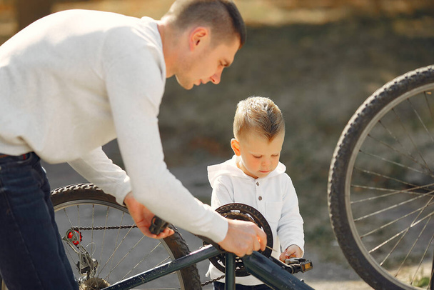 Father with son repare the bike in a park - Фото, изображение