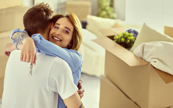 Young happy couple hugging, showing keys to new house - Foto, Imagen