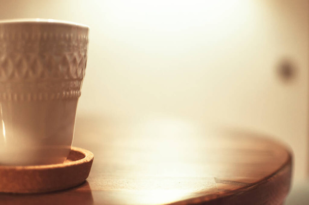 ένα λευκό openwork κύπελλο και πιατάκι με ζεστό καφέ στέκεται σε ένα ξύλινο τραπέζι. Αντιγραφή χώρου. - Φωτογραφία, εικόνα