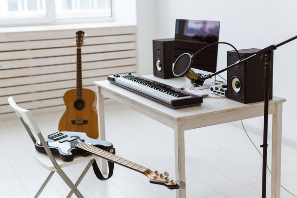 マイク、コンピュータ、楽器のギターとピアノの背景。ホームレコーディングスタジオのコンセプト. - 写真・画像
